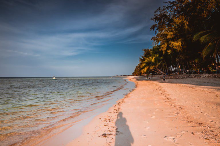 Photographer's shadow on the empty sand of a wide Sumba beach