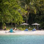 Jungle-backed beach with parasols and guests on the sand