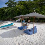 Parasols, bean bags and a low table set out on white sand