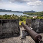 Old cannon on a fort wall looking out over the bay and village