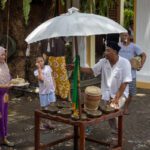 Villagers in traditional dress with a ceremonial parasol and drum