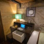 Cabin desk with a laptop, lamp and round mirror above