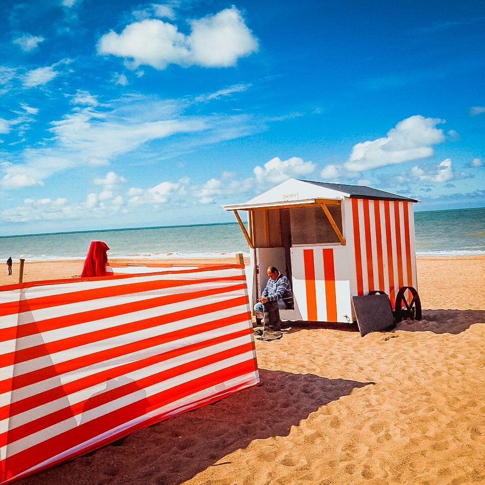 Red-and-white striped beach cabin and windbreak on the sandy beach at De Panne, Belgium