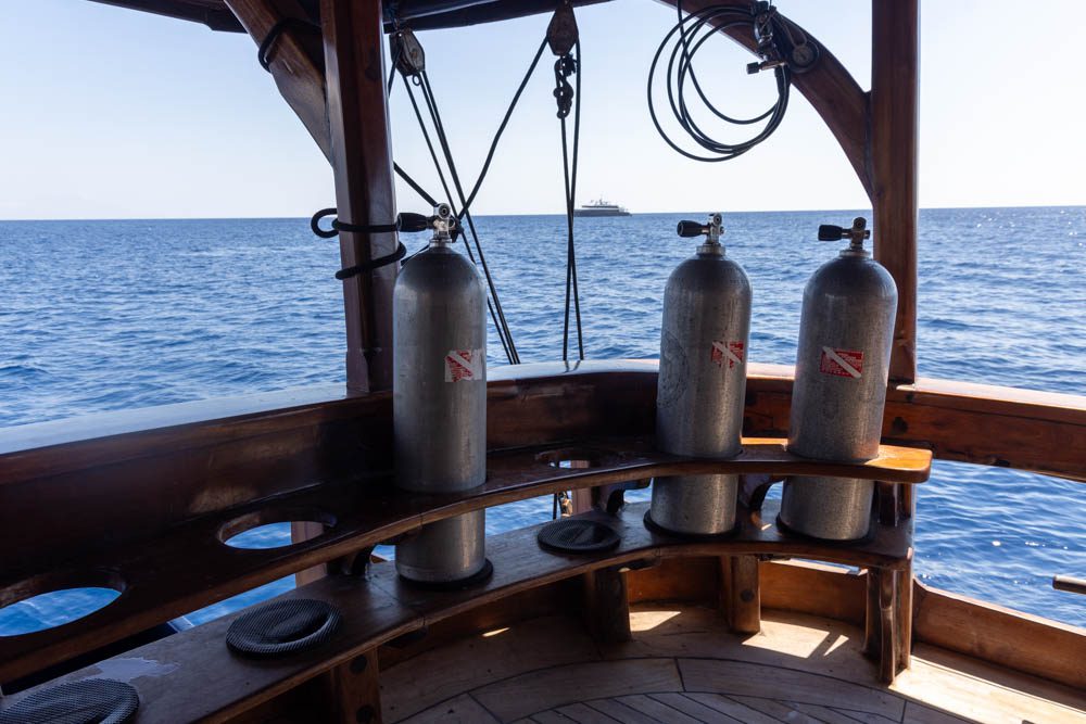 Scuba tanks racked on a liveaboard dive deck that drains straight into the sea, where reef-safe sunscreen for divers washes off between dives