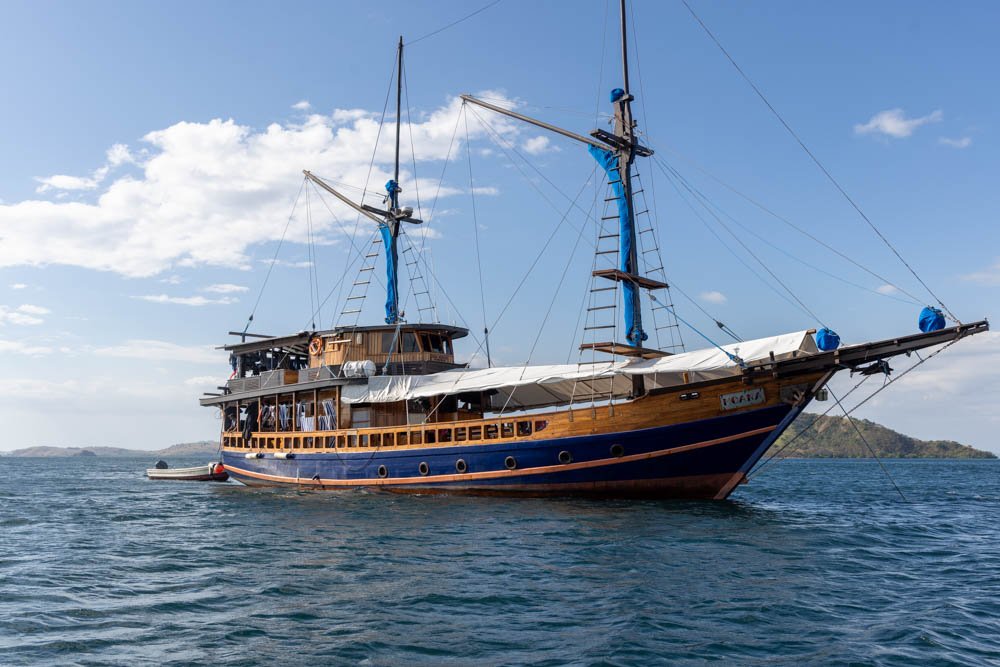 Wooden phinisi liveaboard at anchor on the blue water off Komodo