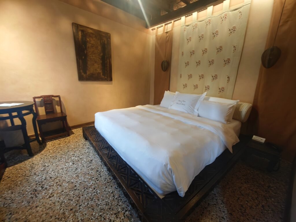 Guest room at Novecento Boutique Hotel in Venice, with a double bed, upholstered headboard and exposed wooden beams