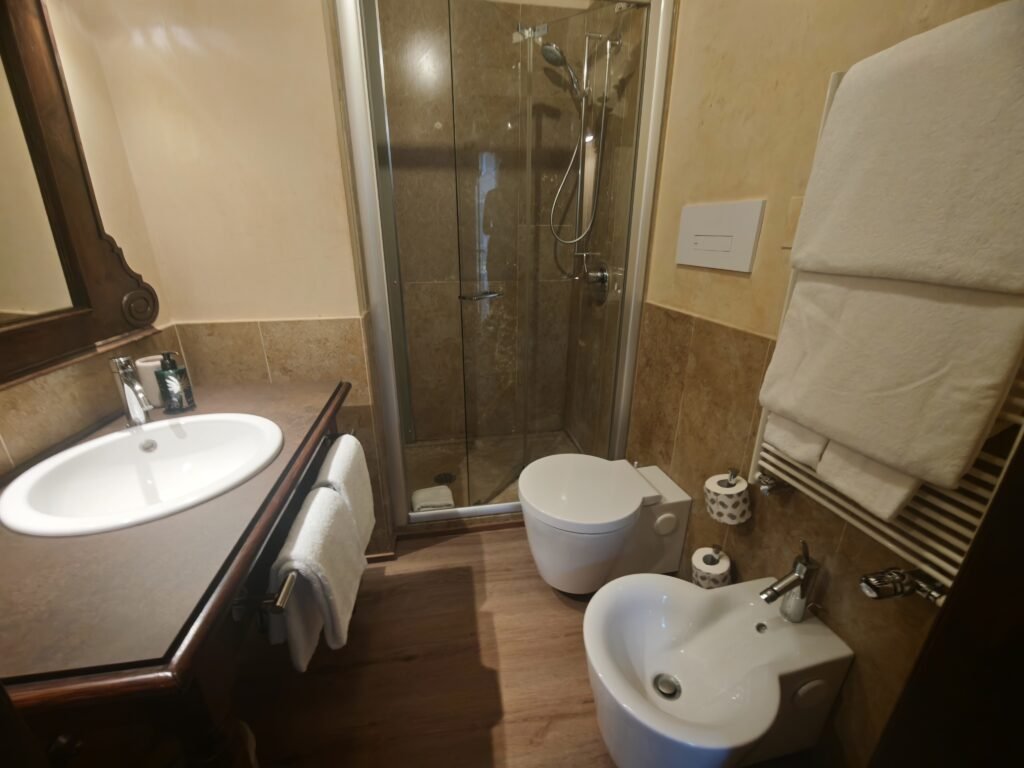 Compact en-suite bathroom at Novecento Boutique Hotel in Venice, with a small shower, basin, bidet and heated towel rail