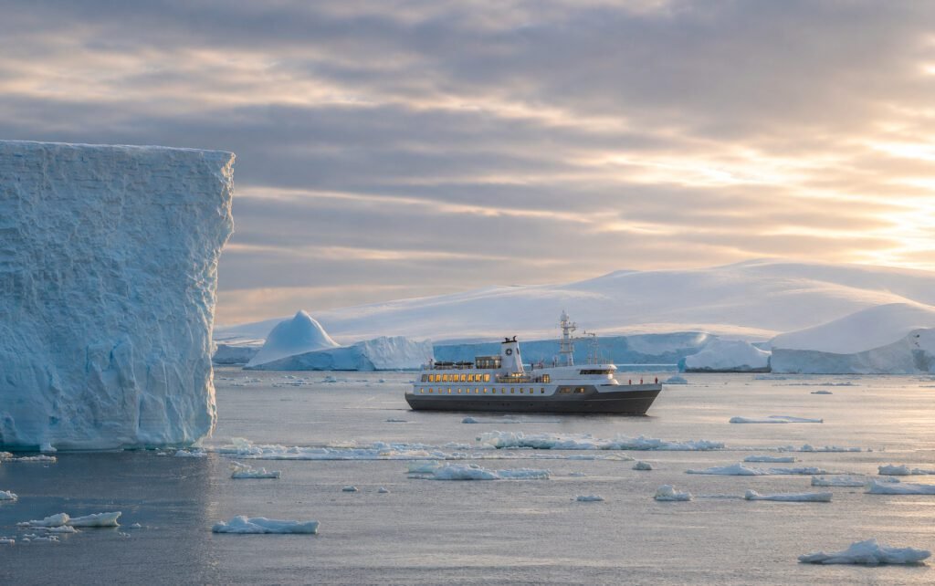Aureum explorer yacht beside an iceberg, Antarctica