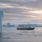 Aureum explorer yacht beside an iceberg, Antarctica