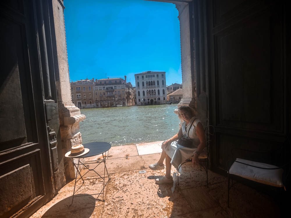Visitor sitting at an open palazzo window overlooking the Grand Canal in Venice