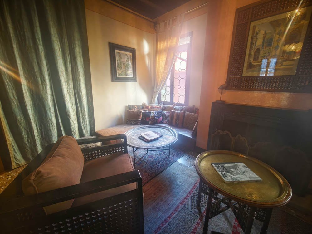 The upstairs living room at Novecento Boutique Hotel in Venice, with green silk curtains, a brass tray table and Fortuny-inspired furnishings