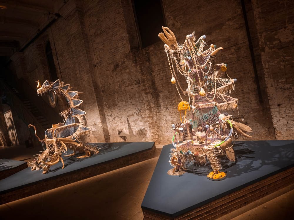 Woven and beaded sculpture installed in a bare palazzo room during the Venice Biennale
