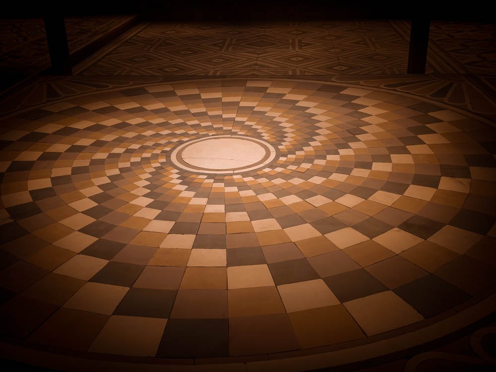Concentric inlaid circular floor in a Venetian palazzo hall used as a Biennale exhibition space