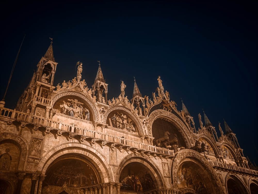 Floodlit facade of St Mark's Basilica at night on Piazza San Marco, ten minutes on foot from Novecento Boutique Hotel