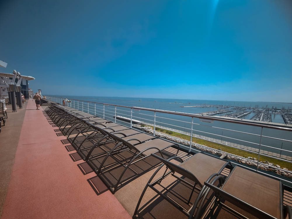 Row of sun loungers overlooking cranes at an industrial cruise berth