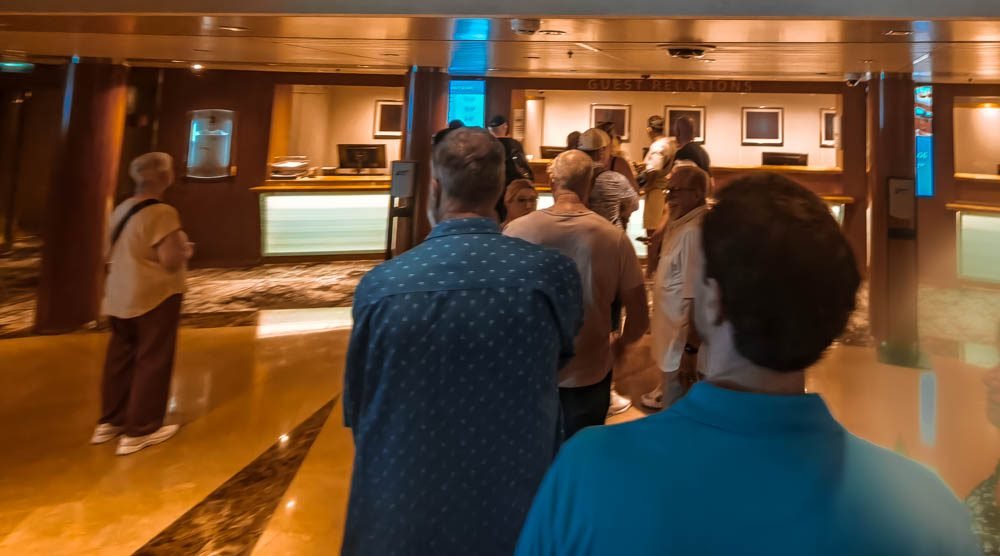 Passengers queuing at a guest services counter on Celebrity Constellation