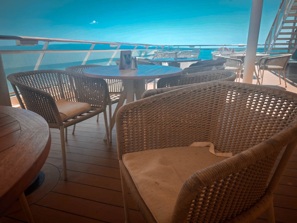 Wicker chairs and table on the veranda of an AquaClass cabin on Celebrity Constellation