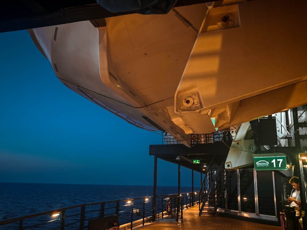 Promenade deck at dusk with lifeboats on Celebrity Constellation