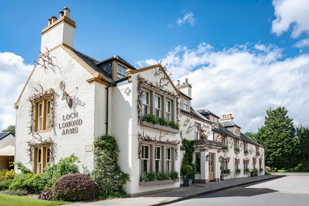 The whitewashed frontage of The Loch Lomond Arms in Luss, hung with red deer antlers