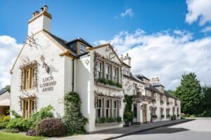 The whitewashed frontage of The Loch Lomond Arms in Luss, hung with red deer antlers