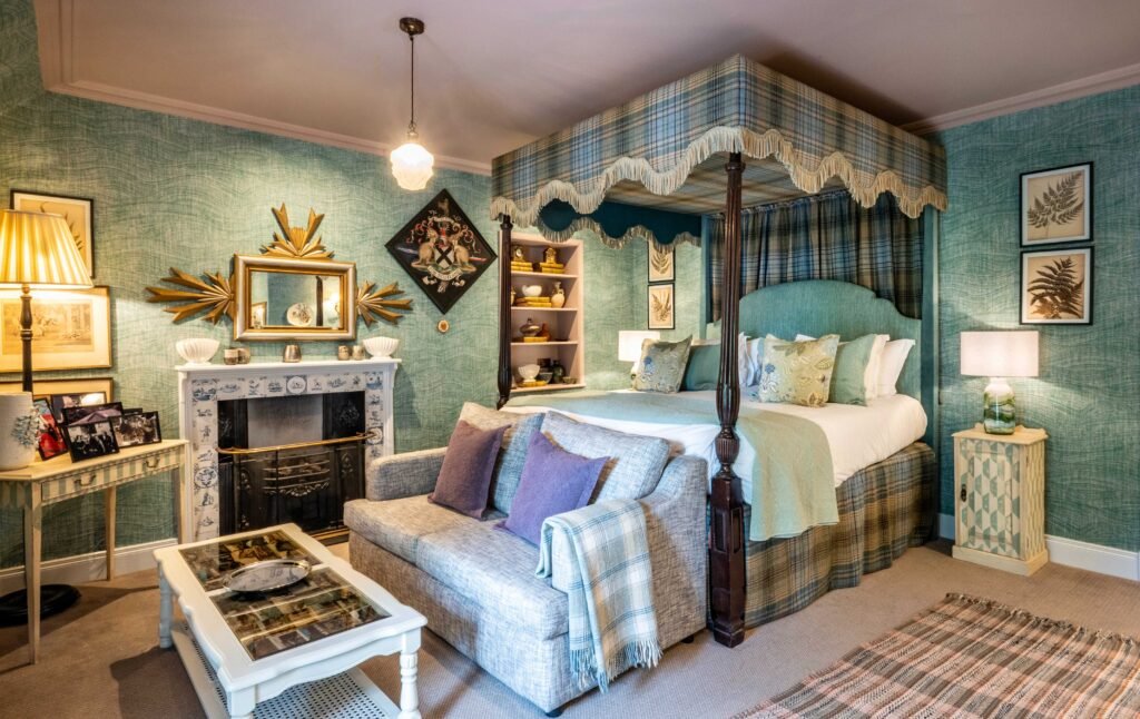 A green tartan-canopied four-poster bedroom at The Loch Lomond Arms with a sofa and tiled fireplace