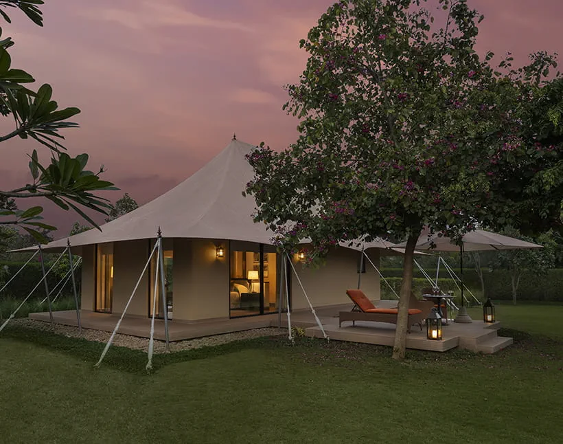 Luxury tent lit at dusk with its private deck at The Oberoi Vindhyavilas Wildlife Resort, Bandhavgarh