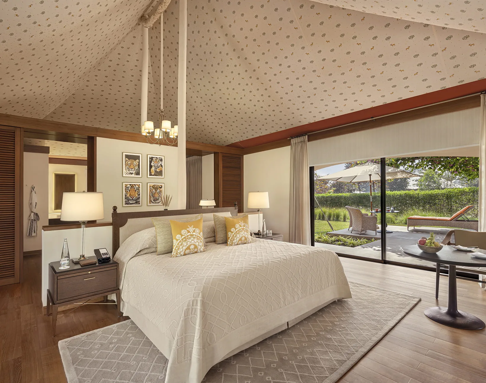 Luxury tent bedroom with canopied ceiling opening onto the garden and private deck at The Oberoi Vindhyavilas Bandhavgarh