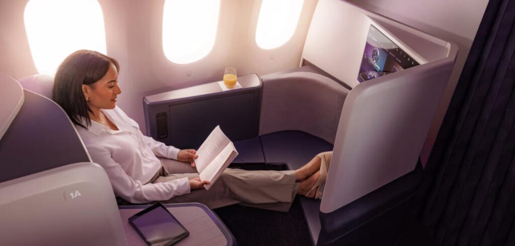 Passenger reading in an Air New Zealand Business Premier Luxe seat beside the 787 windows