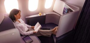 Passenger reading in an Air New Zealand Business Premier Luxe seat beside the 787 windows