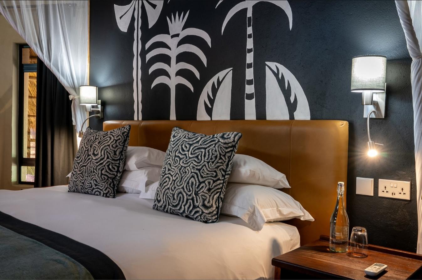 A mosquito-net bed beneath a hand-painted mural in a villa bedroom at Albida - Victoria Falls