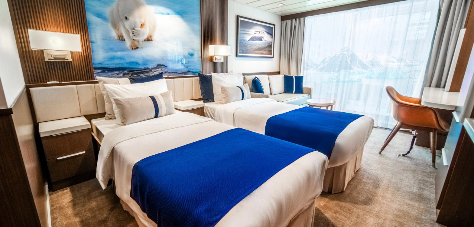 Twin-bed cabin on Douglas Mawson with polar artwork above the beds and a picture window over the ice