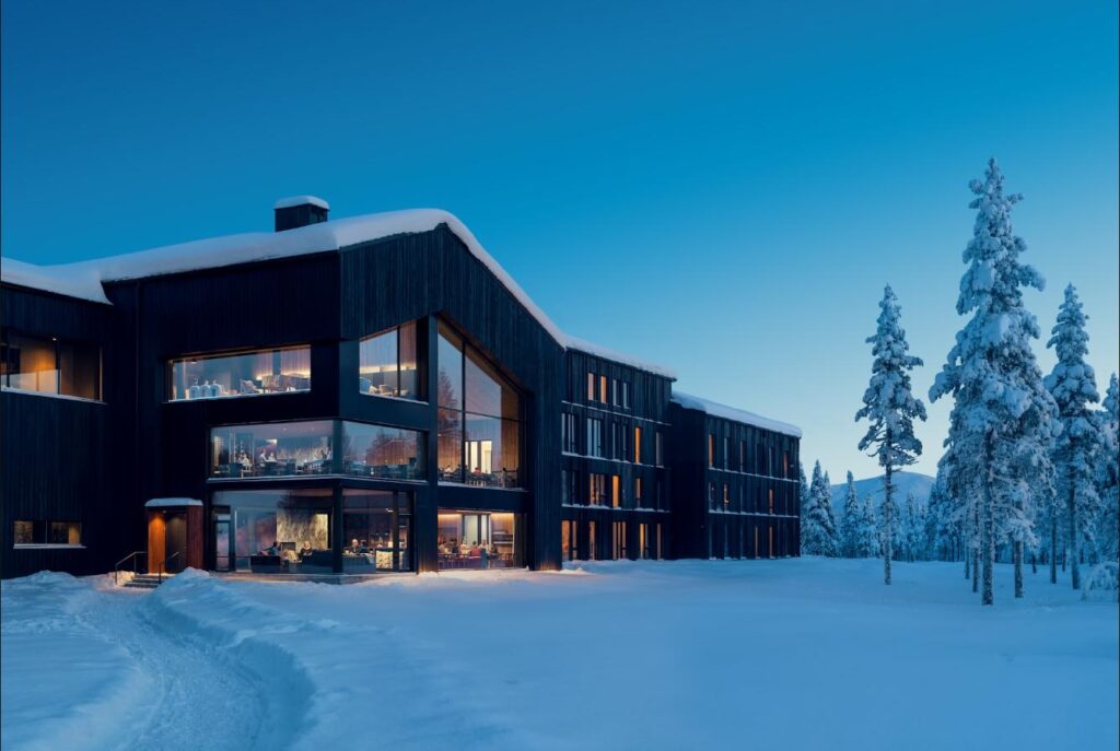 Exterior of Arcora Boutique Hotel & Villas in Torassieppi, Finnish Lapland, lit at blue hour among snow-covered pines