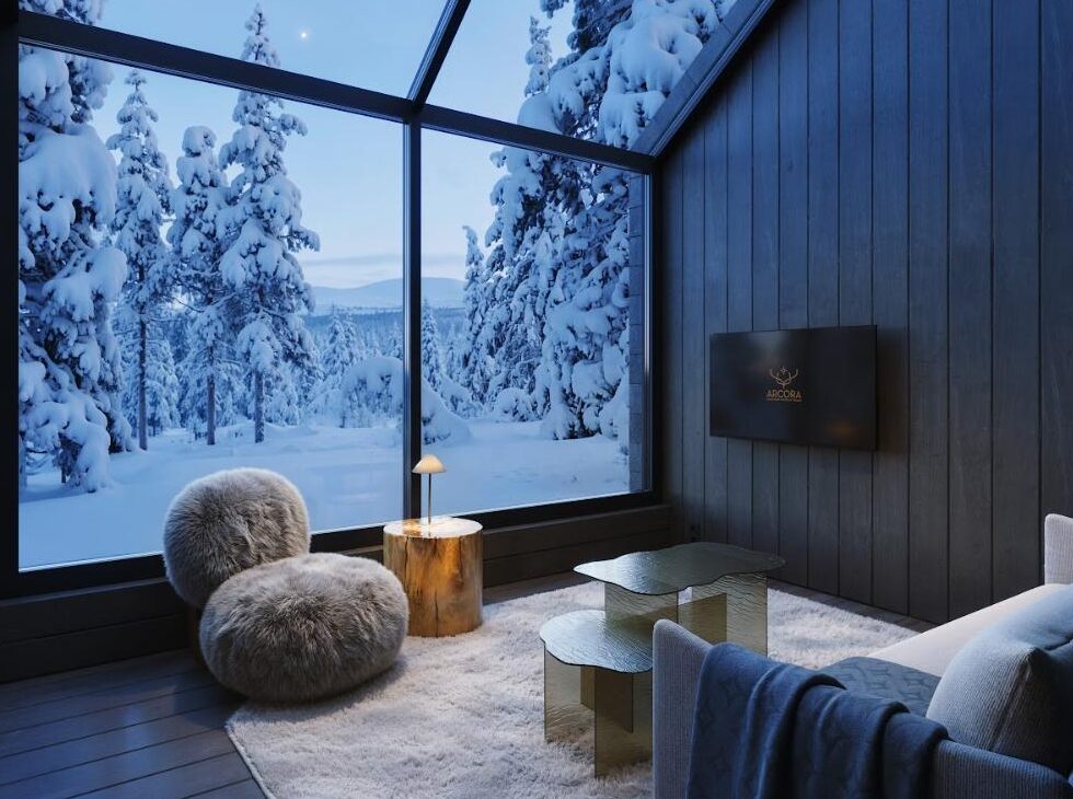Living room of the Arcora Sky Villa Antti, with a glazed gable facing snow-laden trees in Torassieppi