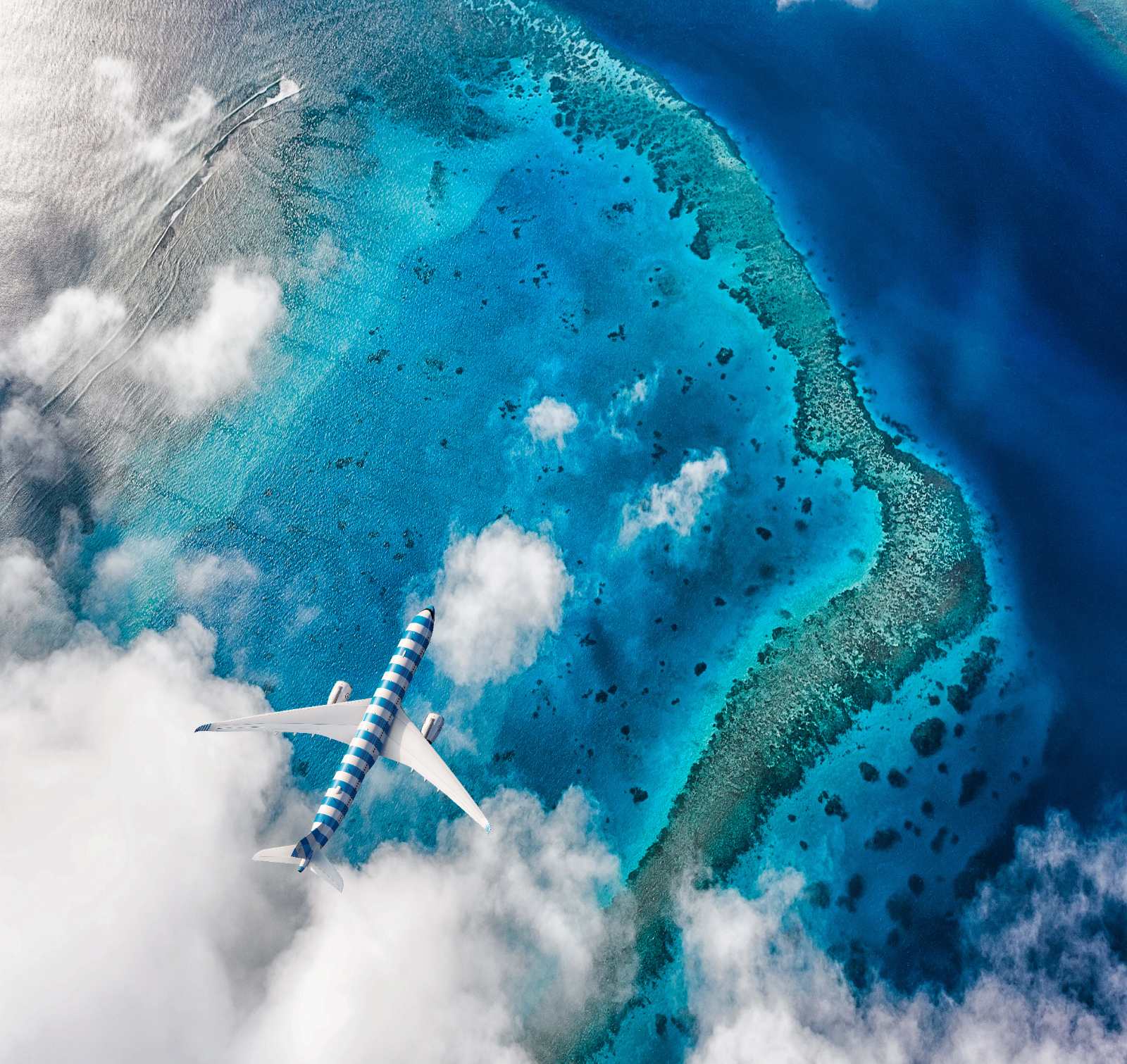 Condor A330neo in striped livery flying over a turquoise coral atoll