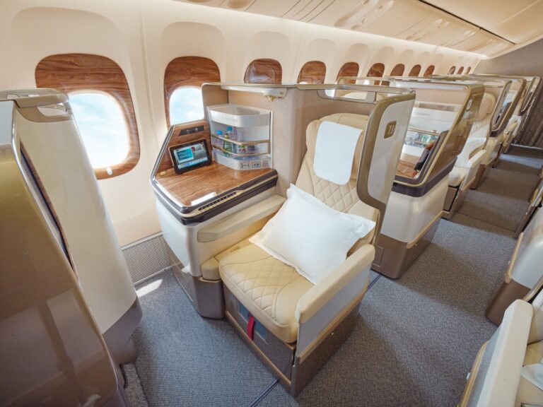 Emirates Is Rebuilding 111 More Aircraft — Here’s What the New 777 Actually Changes Emirates 777 retrofit business class seats in cream leather with wood trim beside the cabin windows