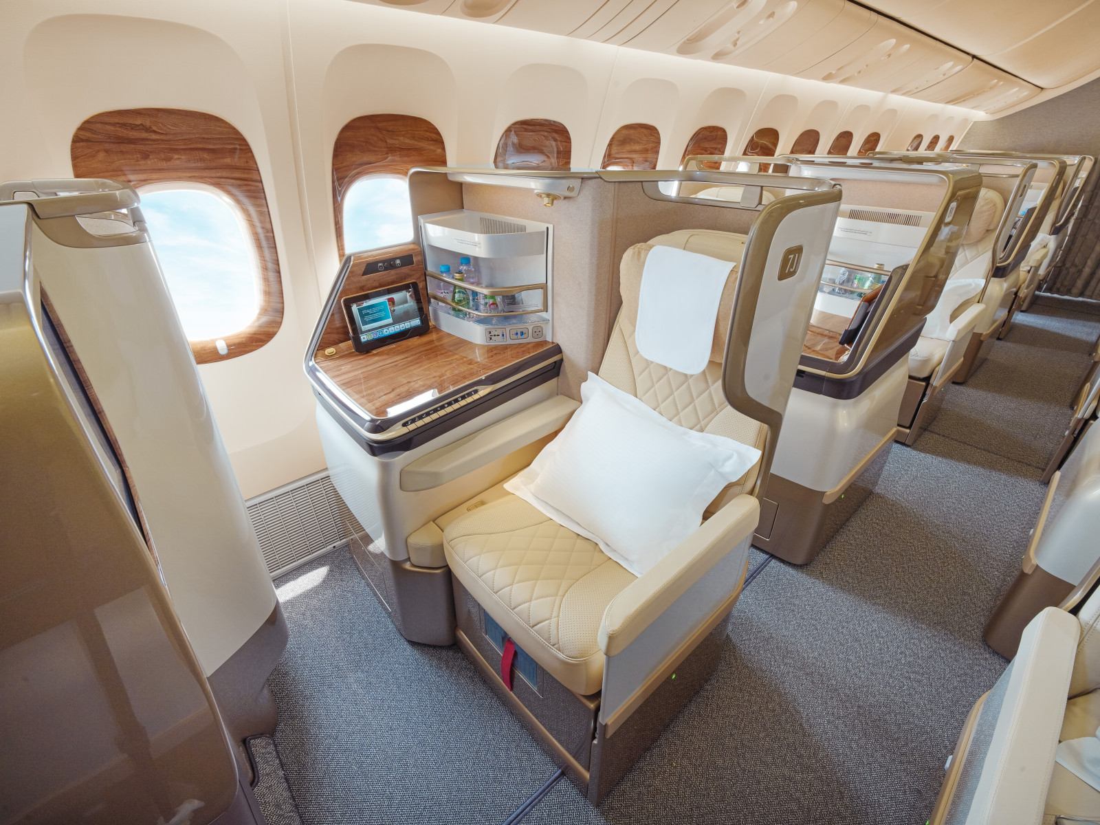 Retrofitted Emirates Boeing 777 Business Class seats in cream leather with wood trim beside the cabin windows