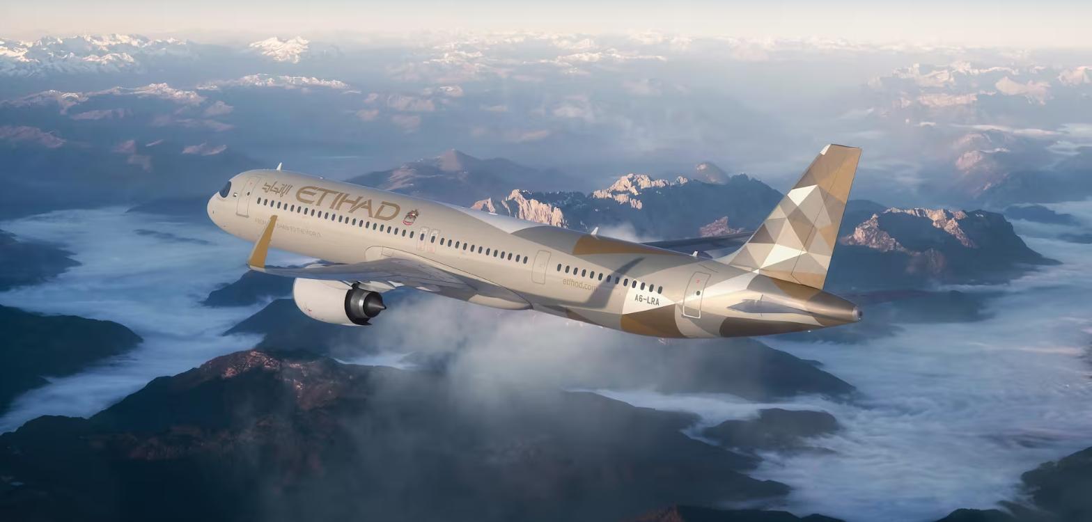 Etihad Airbus A321LR in flight above mountains in the airline’s gold livery