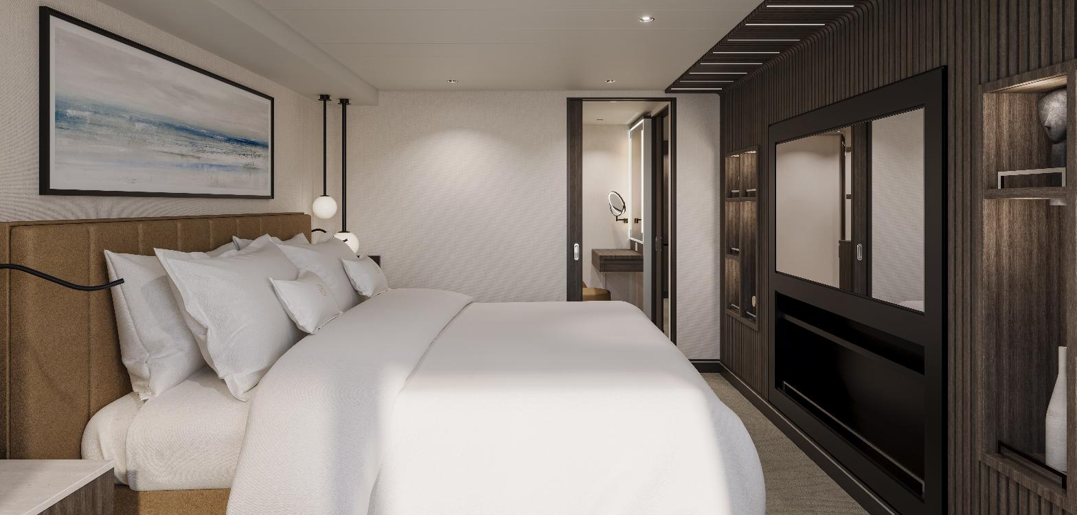 A Cove Residence bedroom on EXPLORA III with a tan leather headboard, white bedding, pendant lights, a dark timber wall with a mirror and fireplace, and an open door to the bathroom