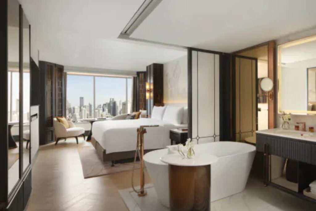 Fairmont Bangkok guest room with freestanding bathtub and floor-to-ceiling views over the Sukhumvit skyline