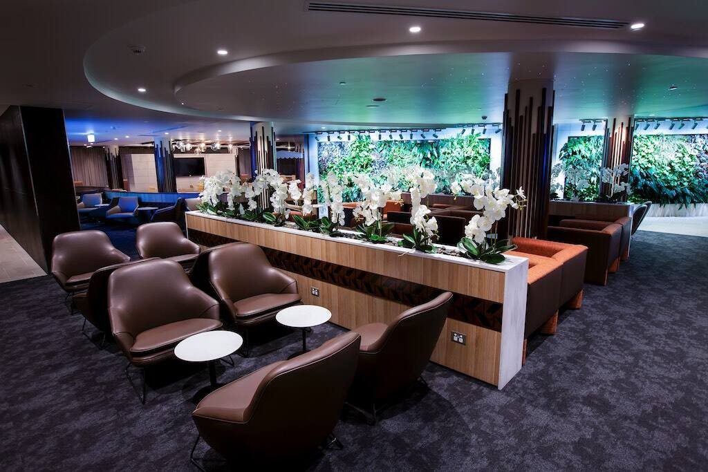 Fiji Airways Premier Lounge at Nadi International Airport, with leather armchairs and an orchid-lined planter