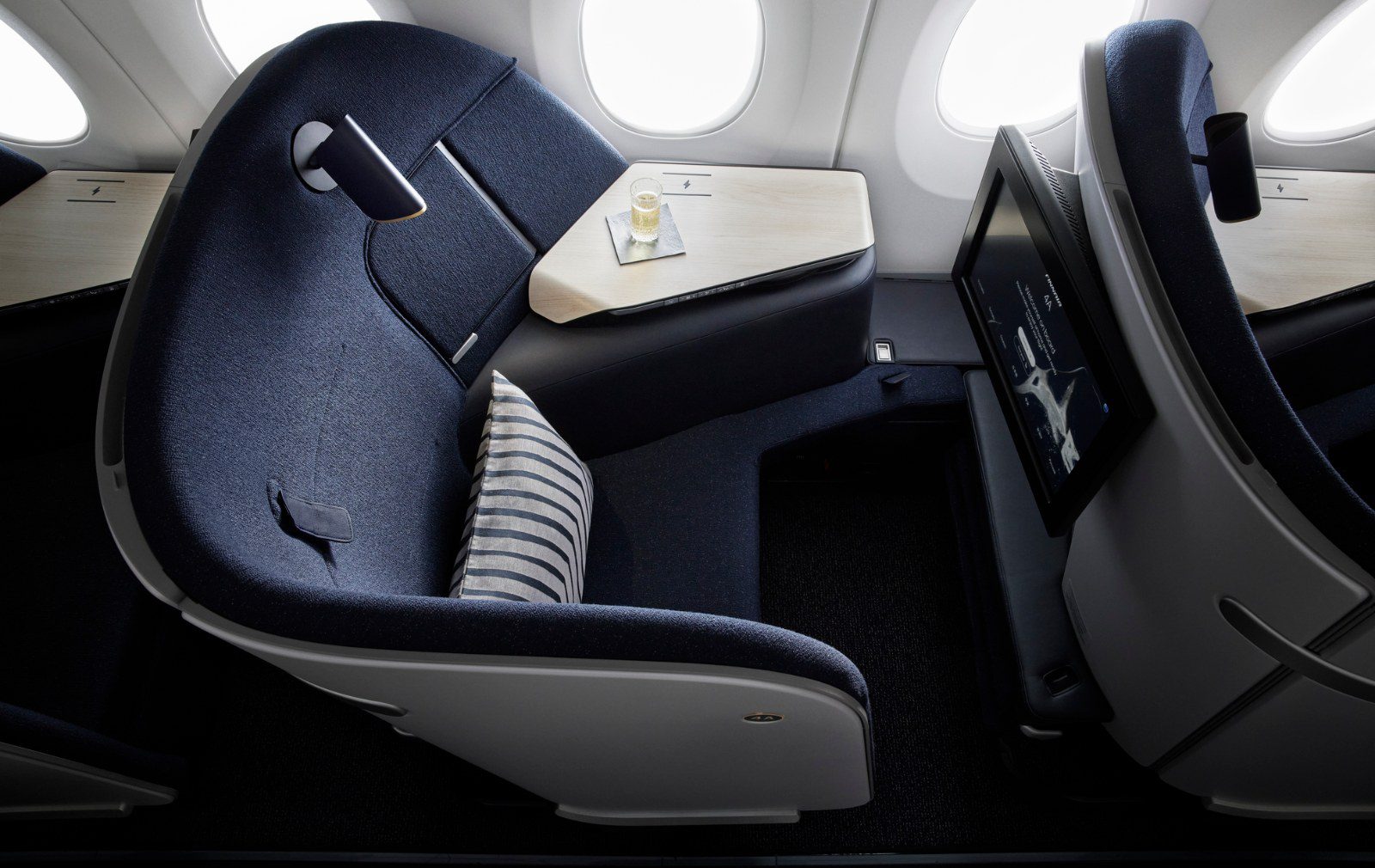 Empty Finnair AirLounge business class seat with a striped cushion and a side table