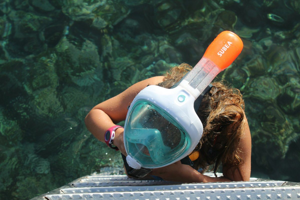 Snorkeller wearing a full-face snorkel mask climbing down a boat ladder into the sea off El Hierro, Canary Islands