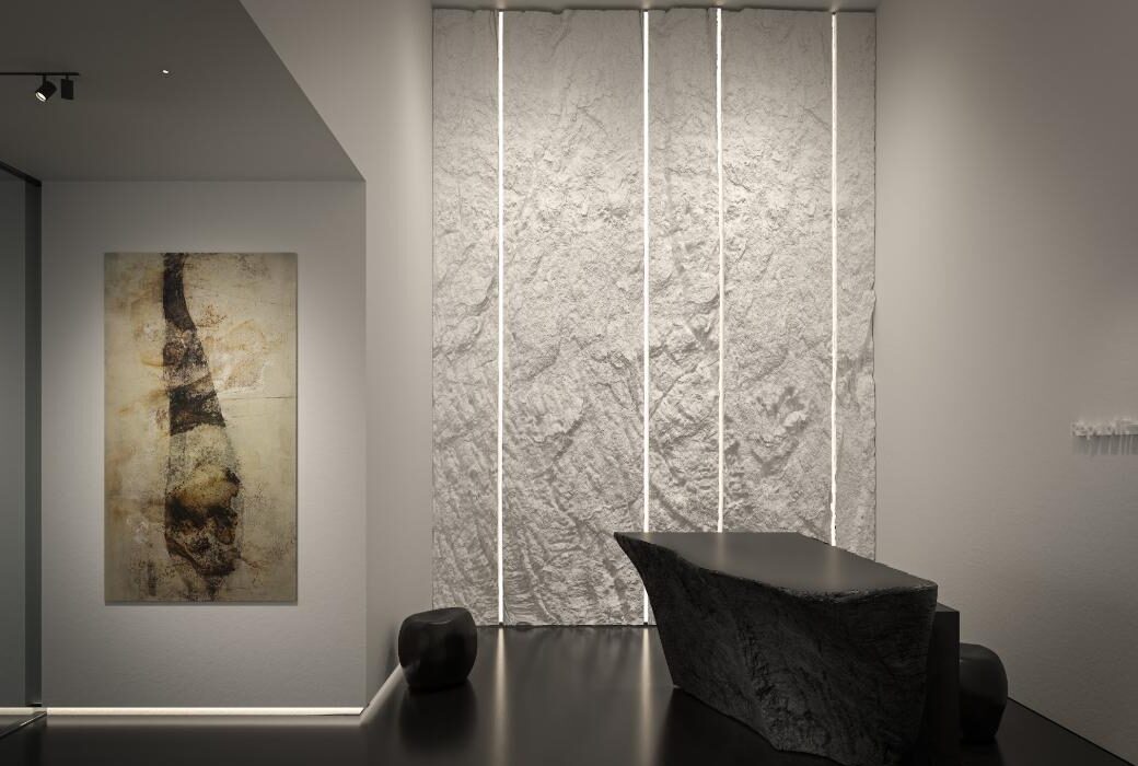 Reception of the coming Magistero wing at Iniala Valletta, with a carved stone desk and backlit limestone wall