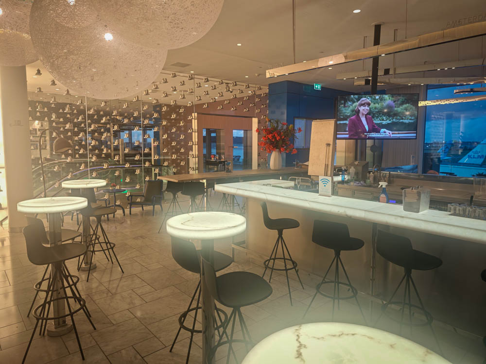 Blue Bar at KLM Crown Lounge 52 with illuminated tables and a wall of Delft houses
