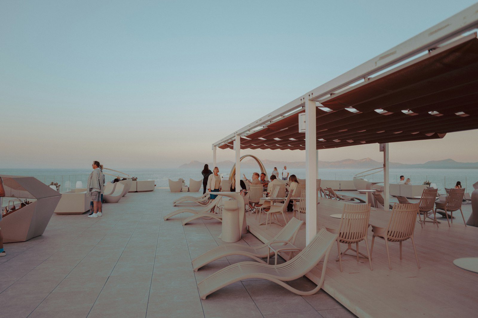 Loungers and low tables at a seaside beach club at dusk