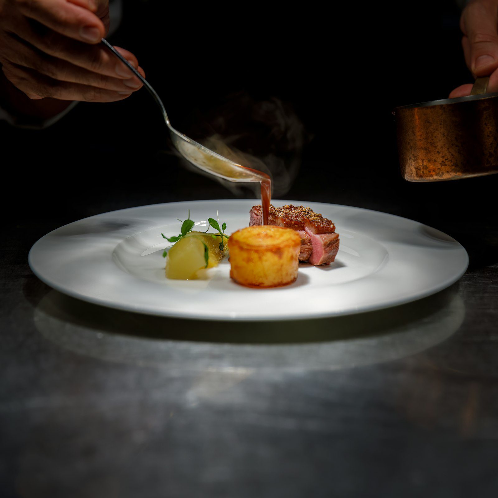 Chef finishing a plate at an intimate fine-dining restaurant
