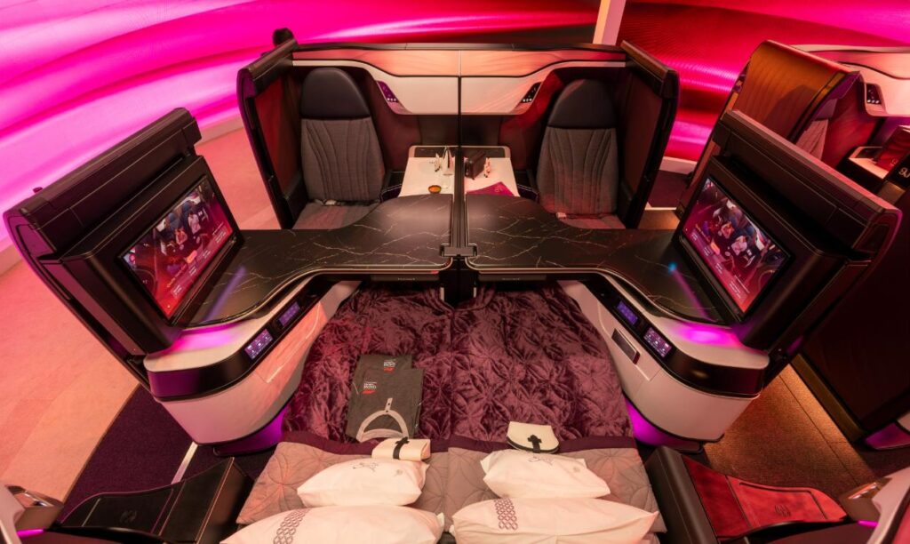 Qatar Airways Qsuite Next Gen quad with the centre dividers down and a double bed made up between two suites