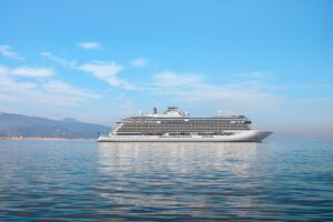 Rendering of Seven Seas Prestige at sea, the new Regent Seven Seas Cruises ship shown off a mountainous coastline