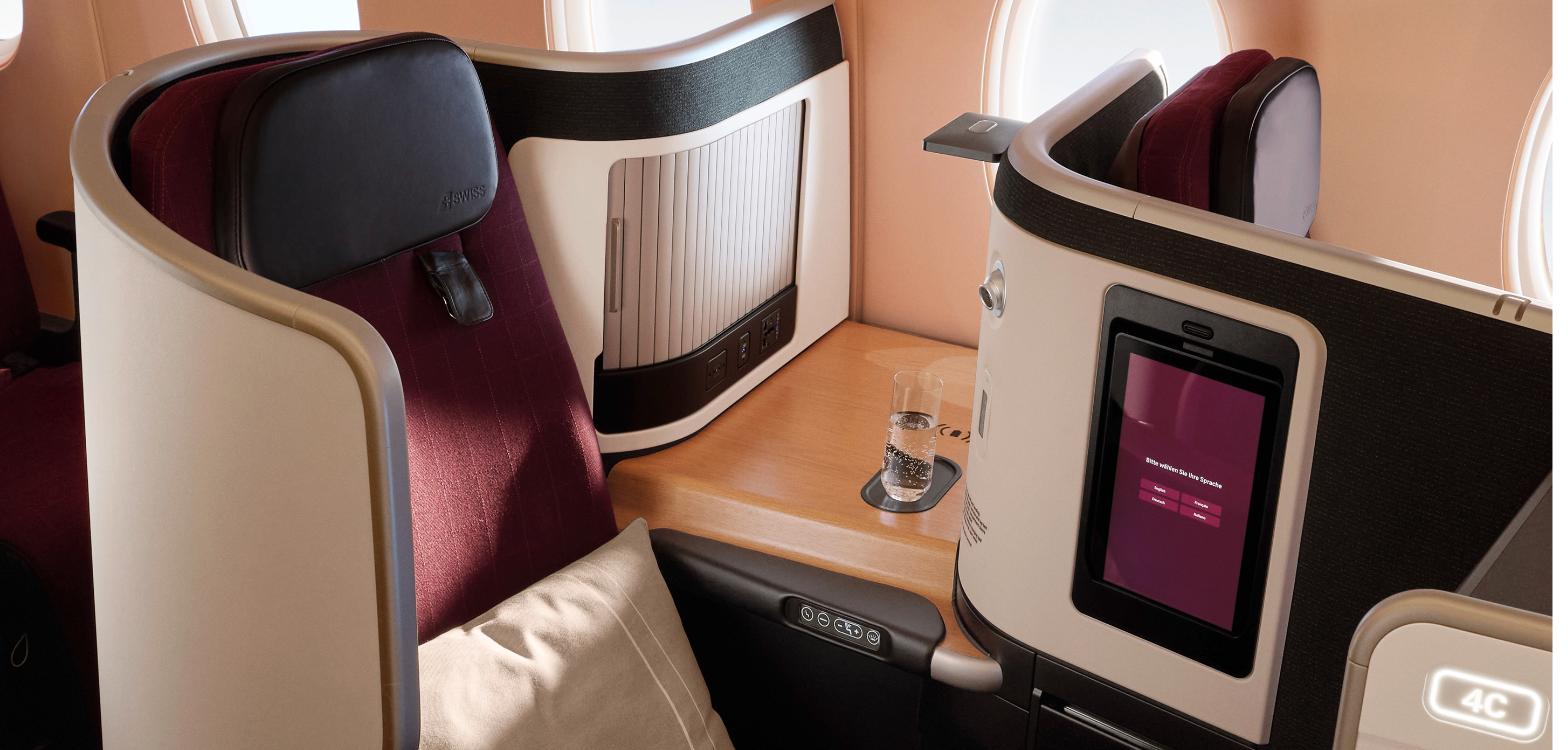 SWISS Senses business class seat in burgundy and cream with a wood side table and tablet screen