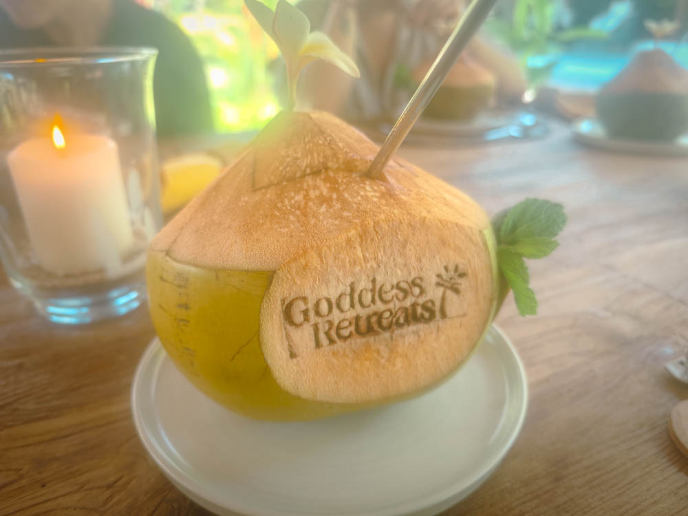 Young coconut stamped with the Goddess Retreats logo, served with a candle on the dining table